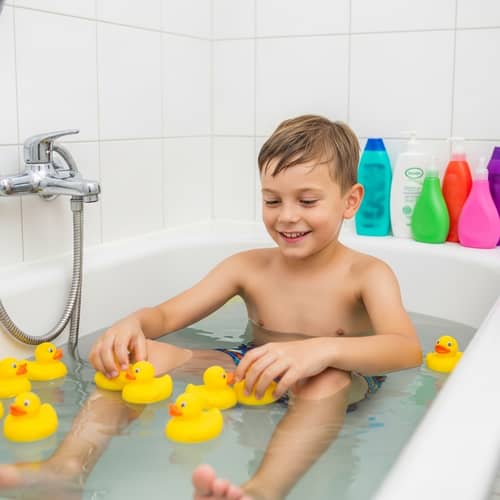 Caucasian Boy in Swimming Trunks Playing in Bathtub