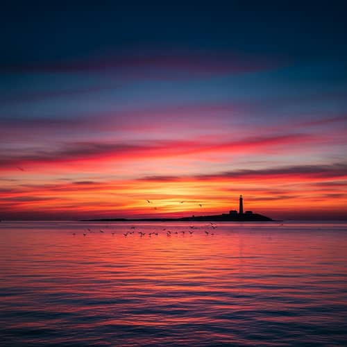 Breathtaking Sunset Over Serene Ocean with Lighthouse