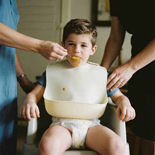 12-Year-Old Boy in High Chair with Diaper and Bib