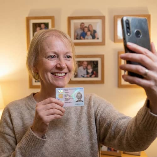 Cheerful Woman Takes Selfie with ID Card Cheerful Woman Takes Selfie with ID Card
