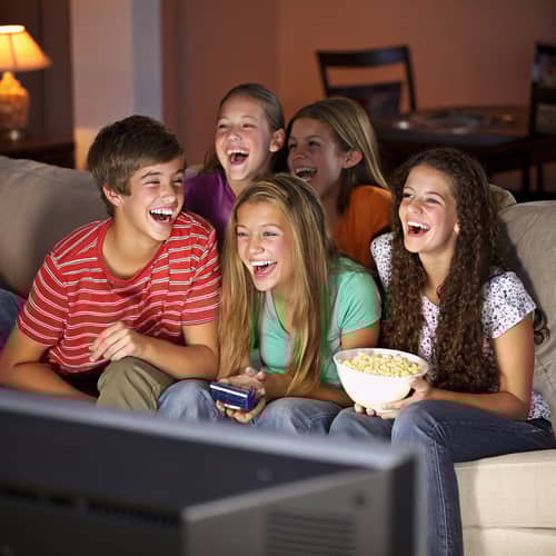 Teenagers Laughing on Couch While Watching TV Teenagers Laughing on Couch While Watching TV