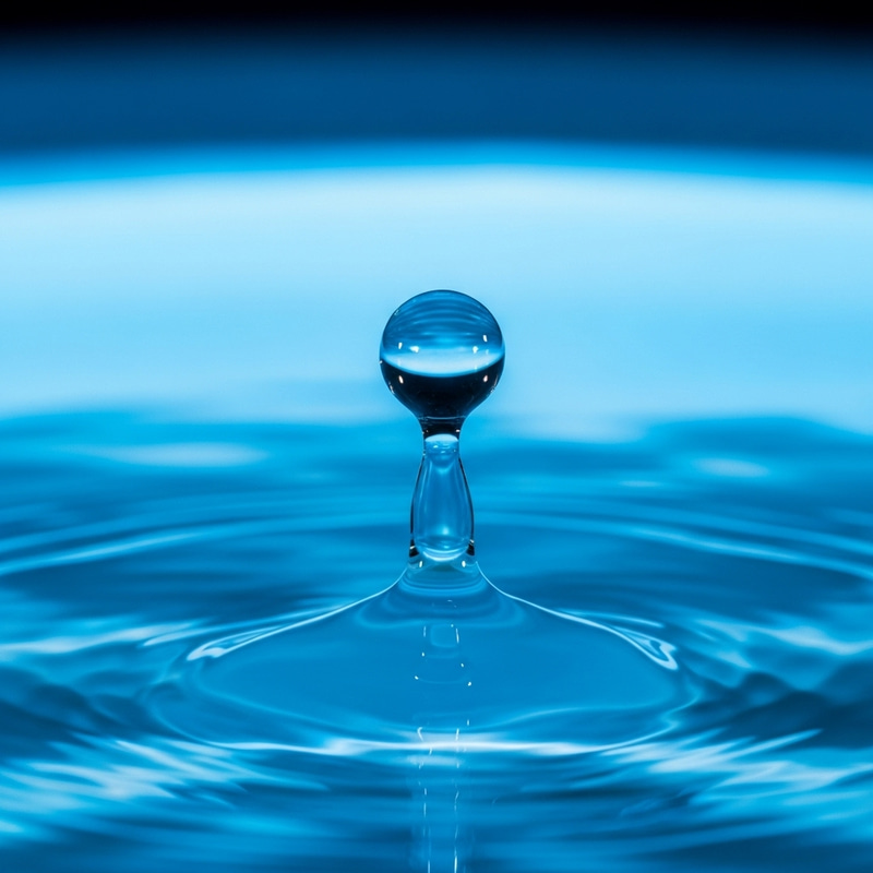 Water Droplet Falling into Fluorescent Blue Fountain