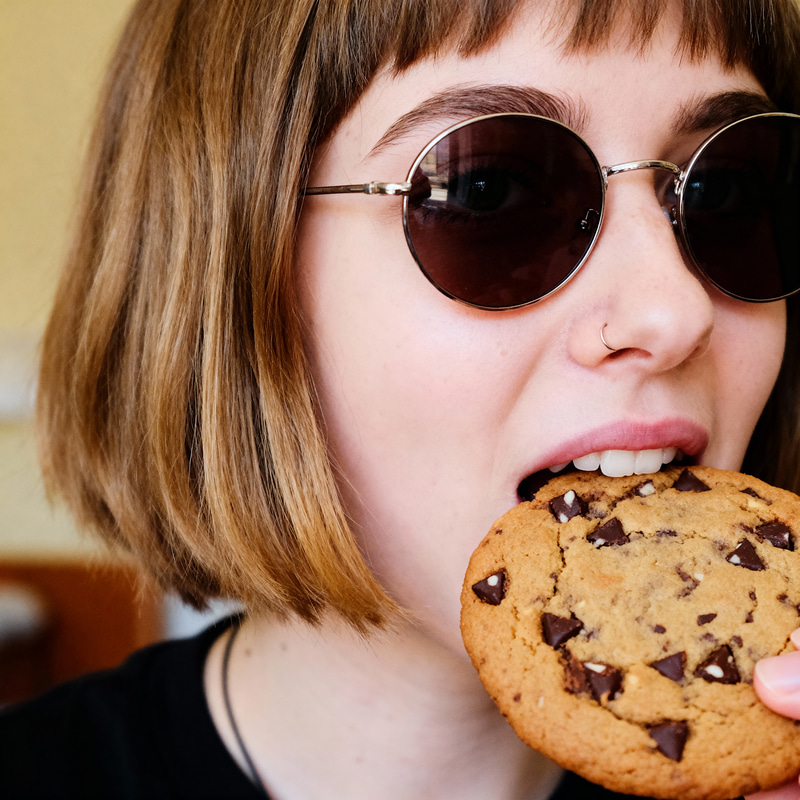 Girl with Sunglasses Enjoying a Chocolate Cookie